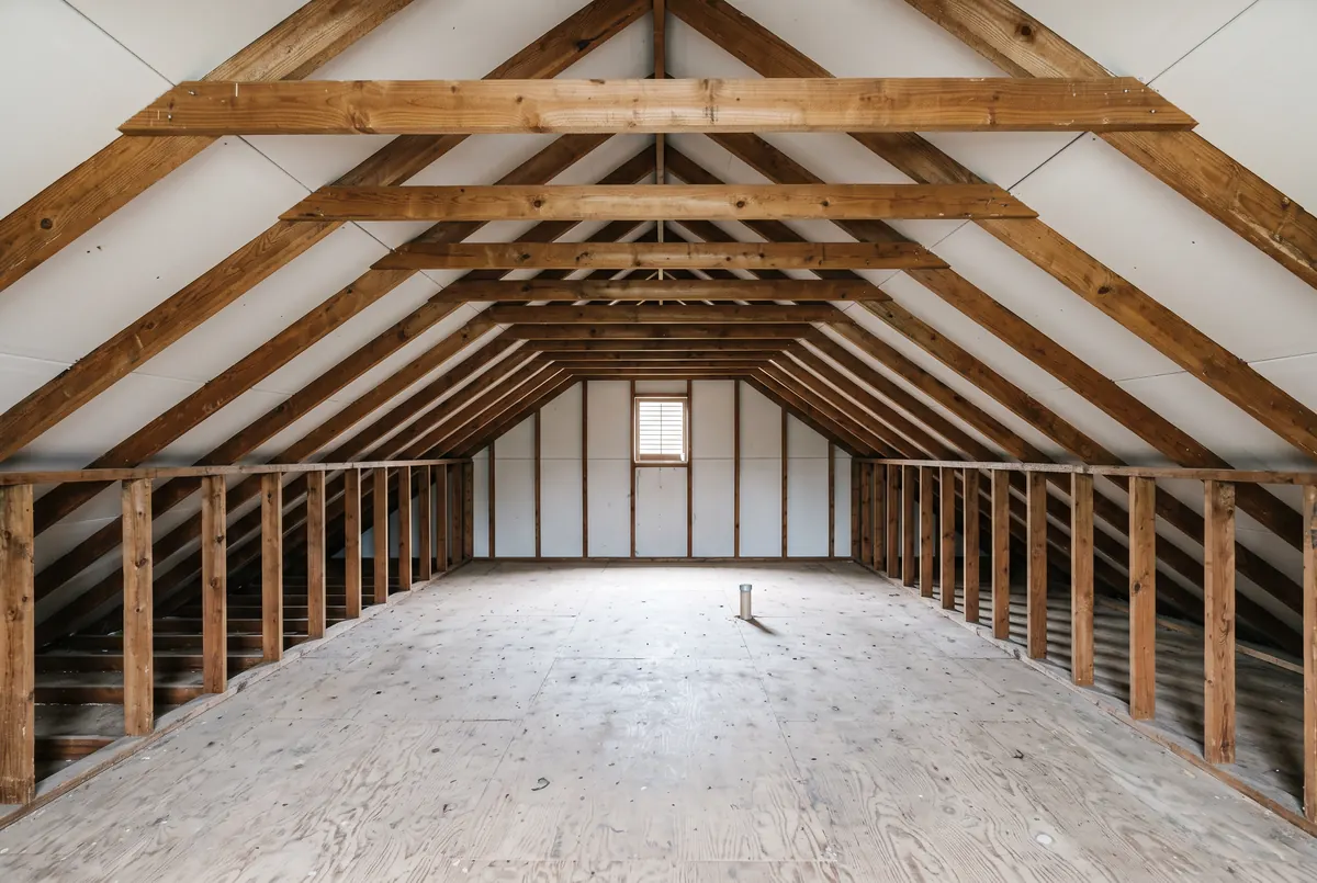 An attic stripped completely to bare wooden ceiling joists with clean exposed drywall between them and no insulation anywhere